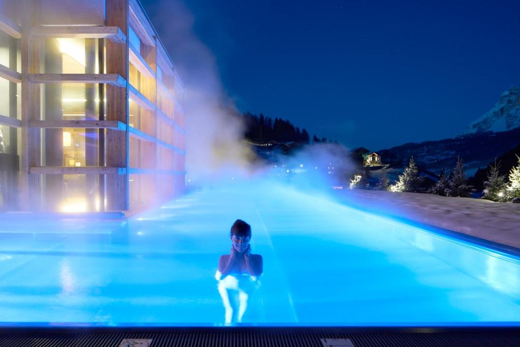 een persoon in een zwembad 's nachts bij Hotel Cristallo - Wellness Mountain Living in La Villa
