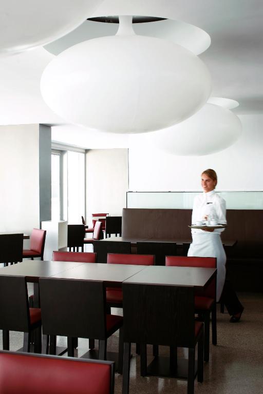 a woman standing in a room with tables and chairs at Troia Design Hotel in Troia