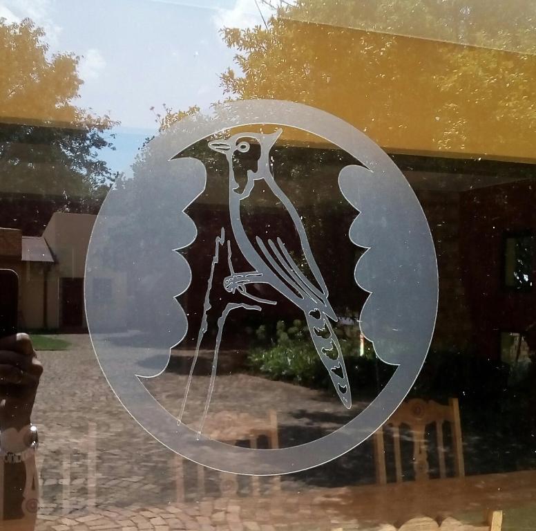 dessin d'un oiseau sur une fenêtre en verre dans l'établissement Woodpecker Guesthouse Middelburg Mpumalanga, à Middelburg