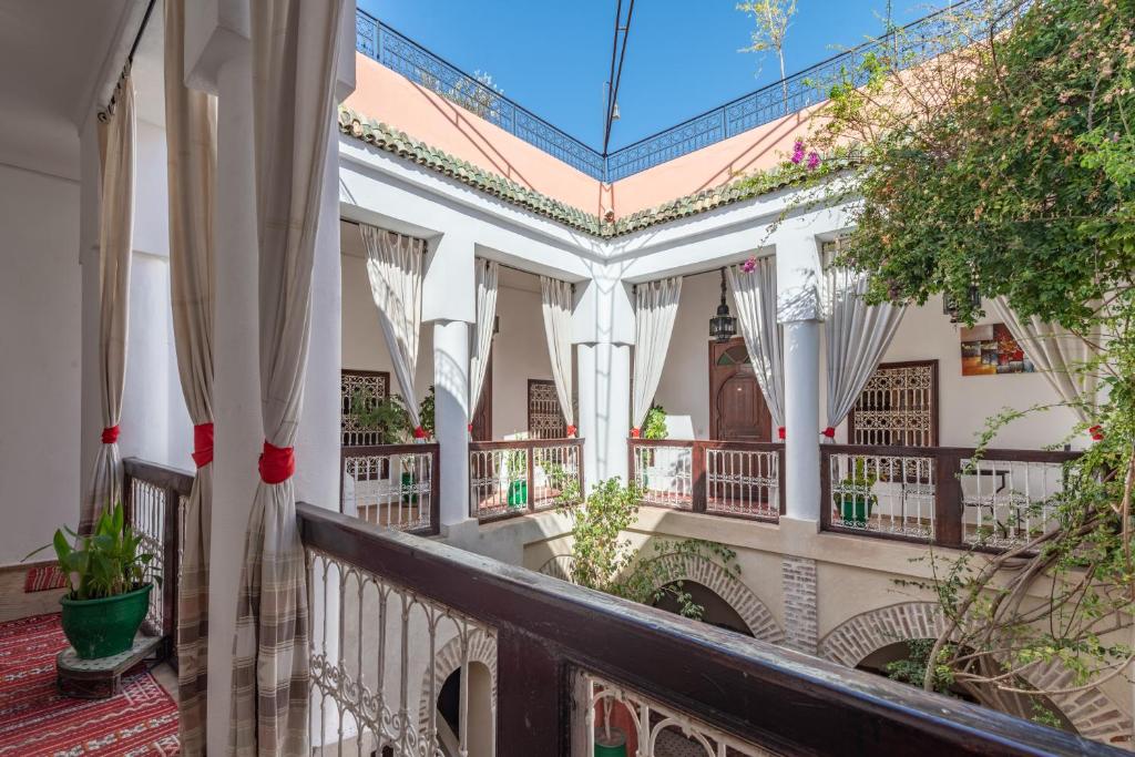 - un balcon d'une maison avec des rideaux blancs et des plantes dans l'établissement Riad Dar Palmyra, à Marrakech