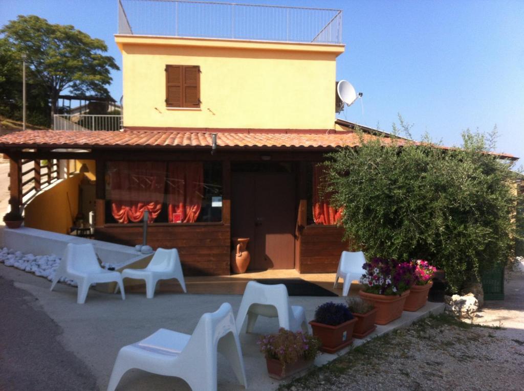 ein Haus mit weißen Stühlen und einem Gebäude in der Unterkunft Il Frantoio in Lapedona