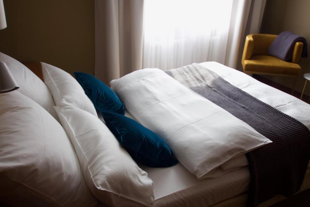 a white bed with blue pillows and a window at Hotel Tari in Würzburg