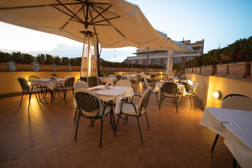 a patio with tables and chairs and an umbrella at Hosianum Palace in Rome