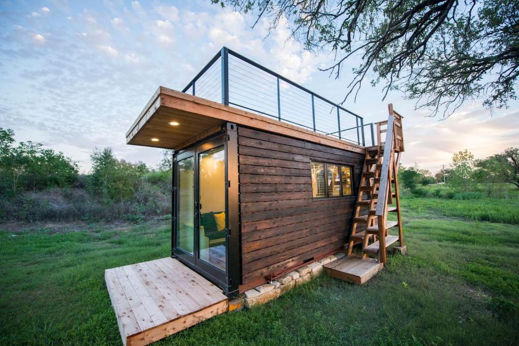 ein winziges Haus mit einer Treppe auf einem Feld in der Unterkunft Elegant Container Tiny House Yellow & Blue in Waco