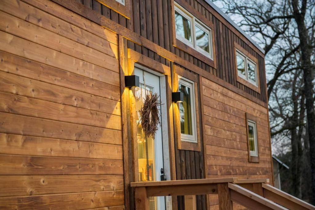 een houten huis met een voordeur met gele bogen bij Montana Escape Elegant Tiny House in Waco Near Magnolia in Waco