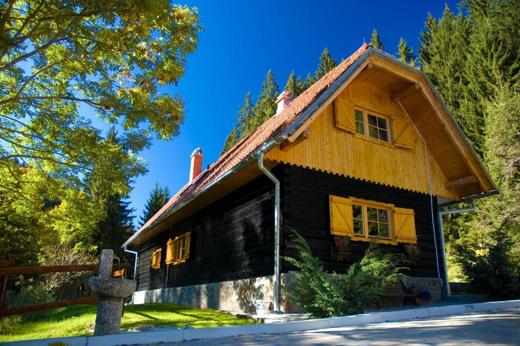 una casa de madera con techo de gambrel en APARTMENTS ROGLA LUKANJA 1, en Oplotnica