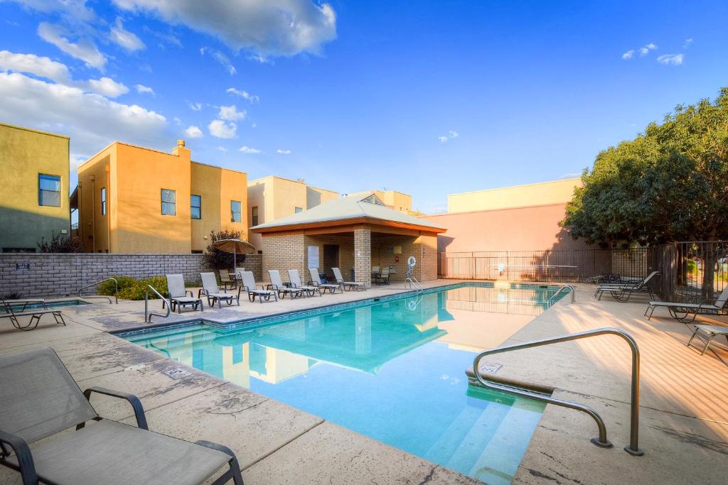 a swimming pool with chairs and a building at Casa San Miguel in Tucson