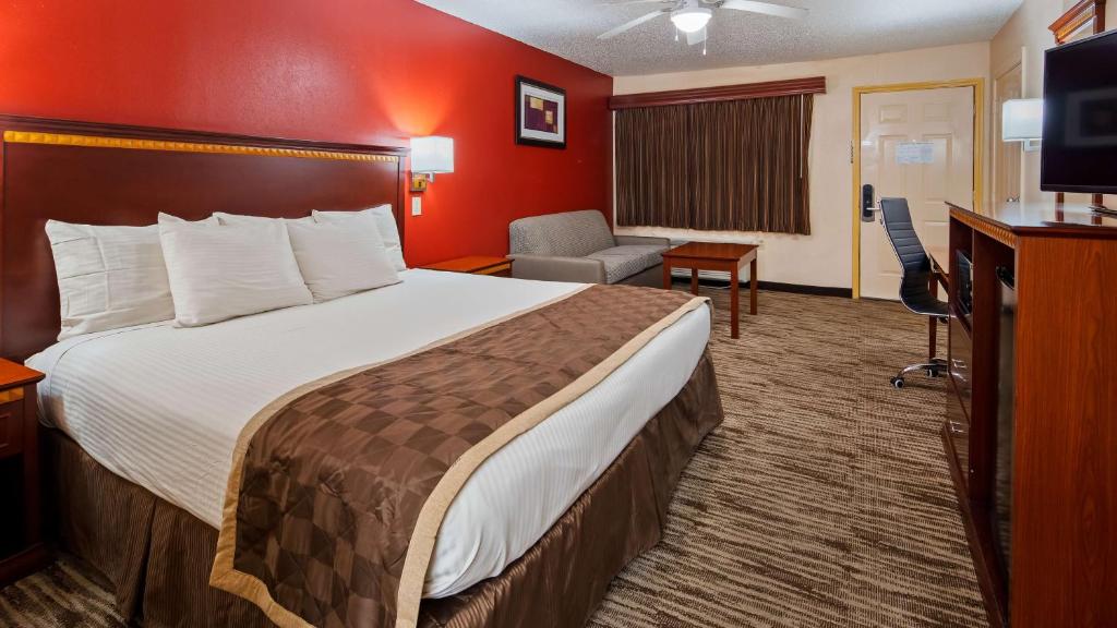 Una habitación de hotel con una cama grande y un televisor. en Best Western Executive Inn, en Marshall