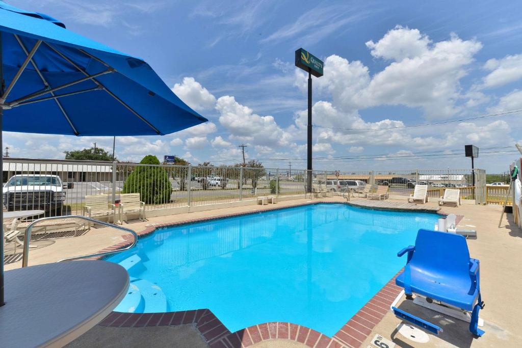 ein großer Pool mit Stühlen und einem Sonnenschirm in der Unterkunft Quality Inn in Gonzales
