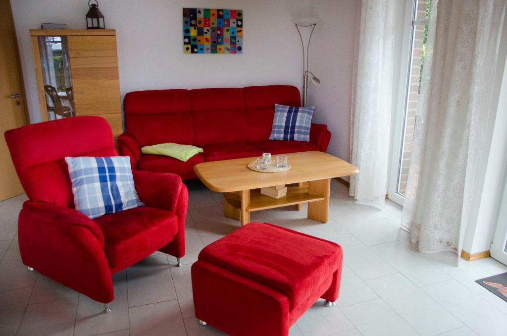 - un salon avec un canapé rouge et une table dans l'établissement Ferienwohnung Nordseeglueck, à Hooksiel