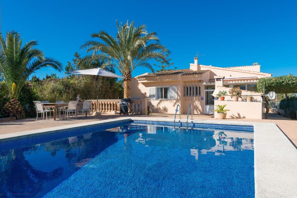 - une piscine en face d'une maison avec des palmiers dans l'établissement Can Moragues & Martorell, à Badia Blava