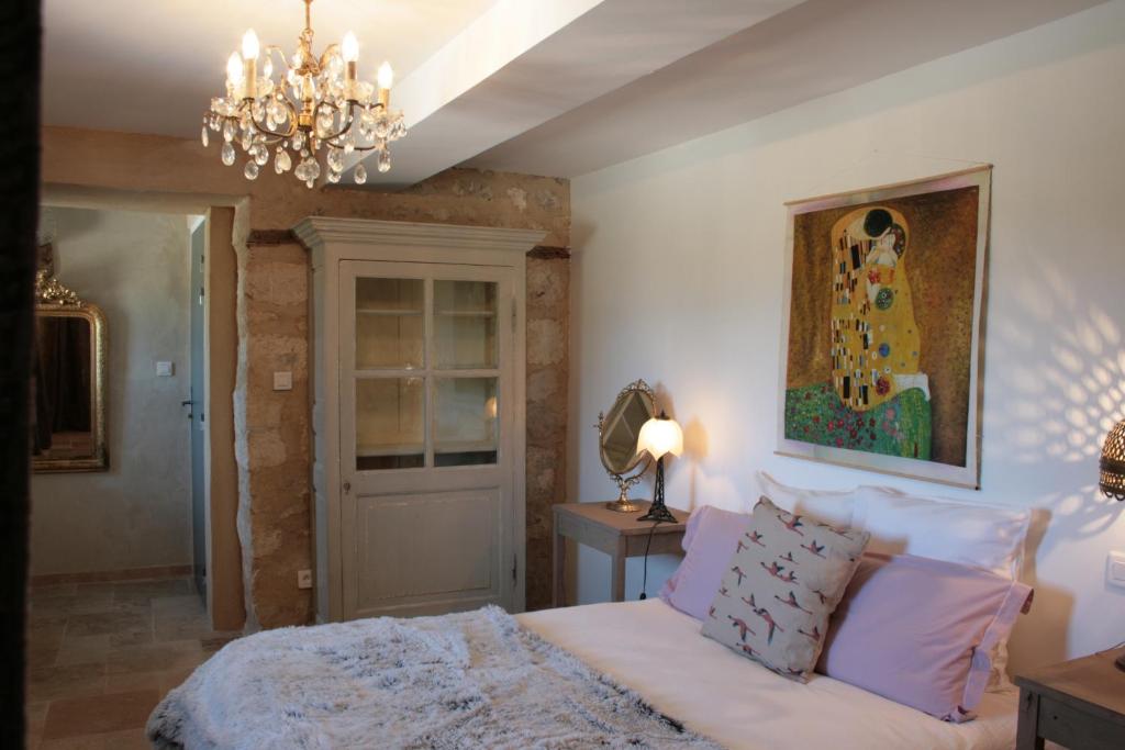 a bedroom with a bed and a chandelier at AU NID DES VIGNES in Cahuzac-sur-Vère