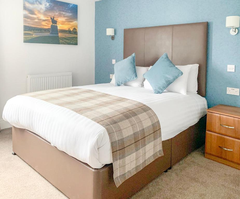 a bedroom with a bed, a desk and a painting on the wall at King Robert Hotel in Stirling