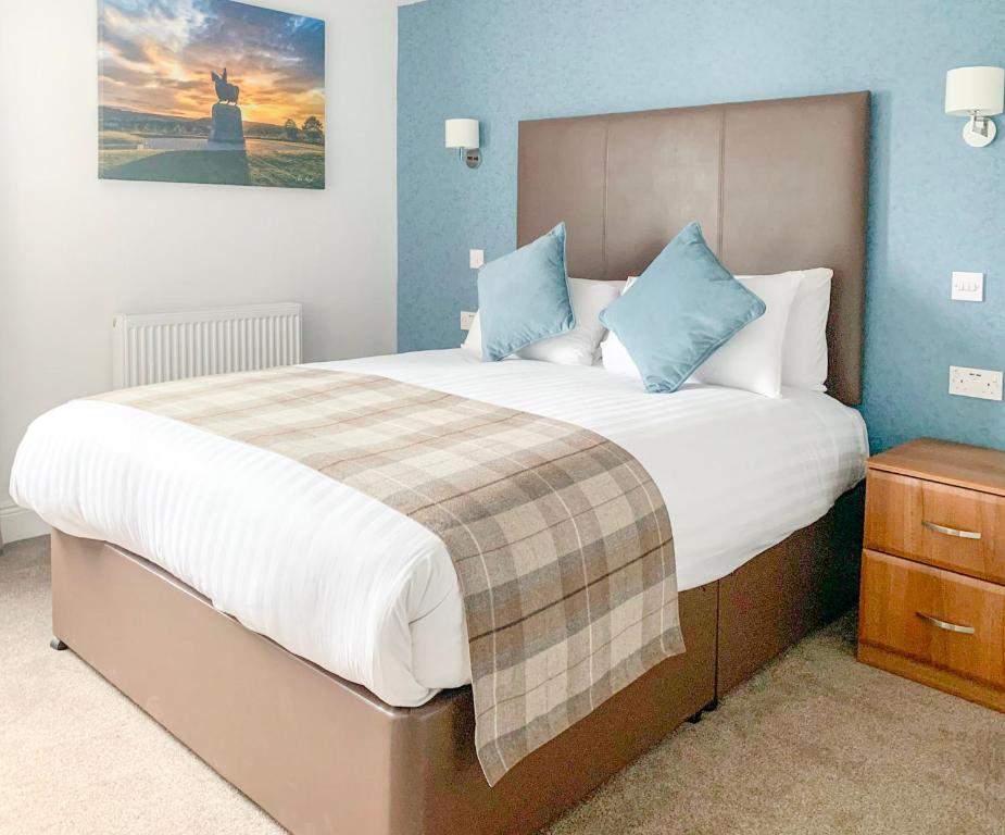 1 dormitorio con 1 cama grande y paredes azules en King Robert Hotel, en Stirling