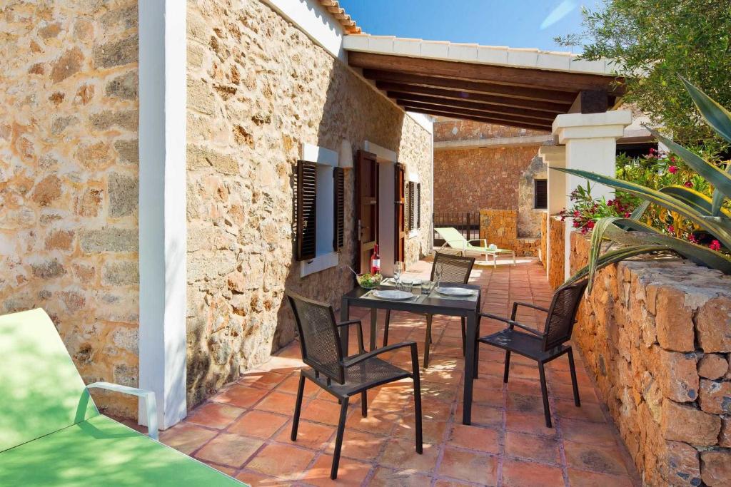 a patio with a table and chairs on a brick wall at Can Noves - Villa de 2 suites in Sant Francesc Xavier