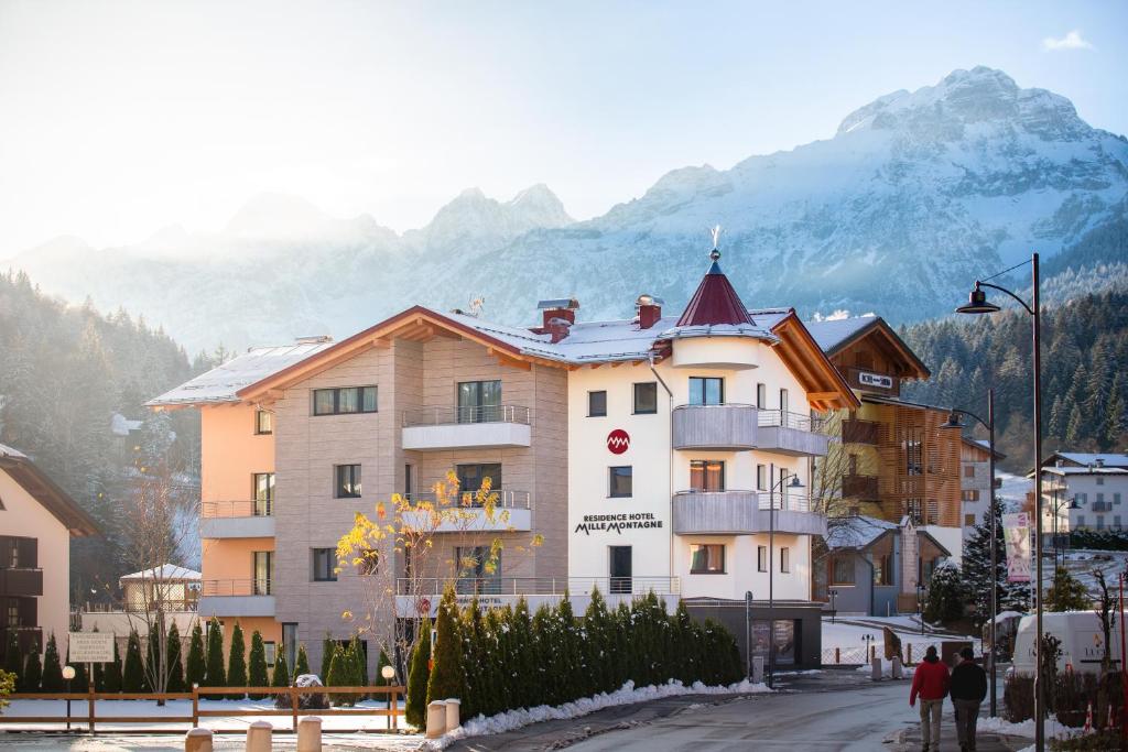 a large building in a town with mountains in the background at Residence Mille Montagne in Andalo