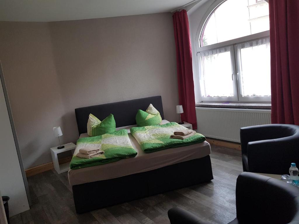 a bedroom with a bed with green pillows and a window at Pension ZWO16 in Zeulenroda