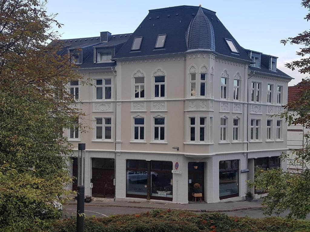 ein großes weißes Gebäude mit schwarzem Dach in der Unterkunft Schillers Hotel & Café - GARNI - in Lüdenscheid