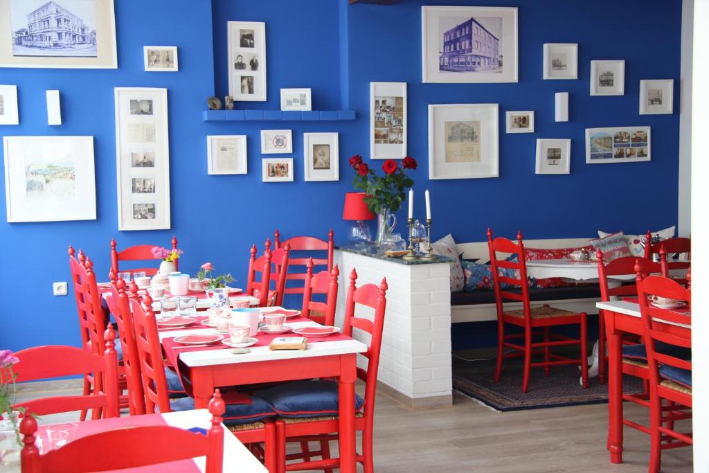 a dining room with red chairs and a blue wall at Villa Westend in Norderney