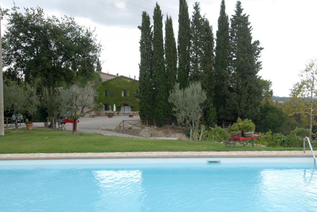 a swimming pool in front of a yard with a house at room in farmhouse near san gimignano in San Gimignano