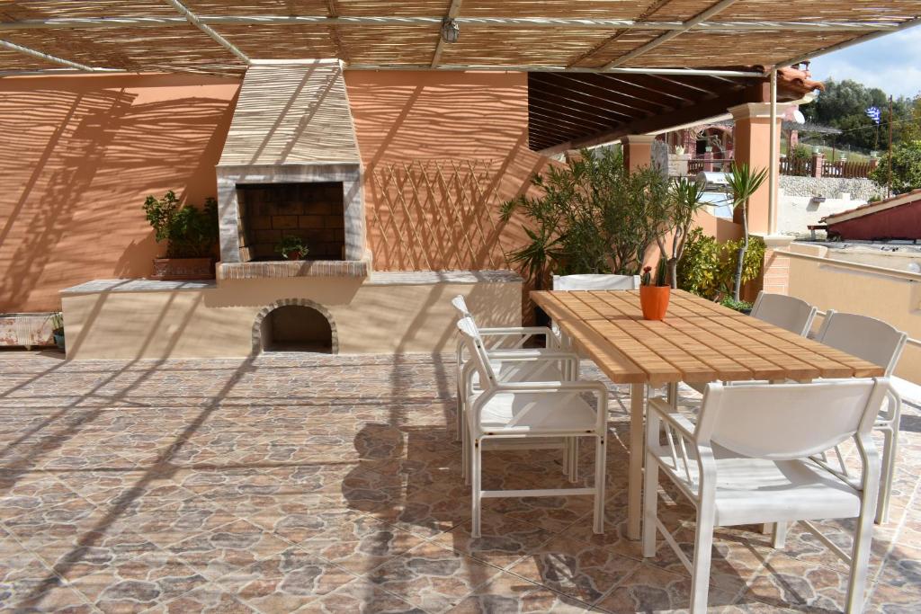 een patio met een tafel en stoelen en een open haard bij Patras Studio in Agios Georgios Pagon