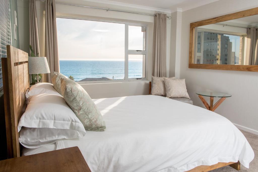 a bedroom with a bed and a window with the ocean at Coral Island in Bloubergstrand
