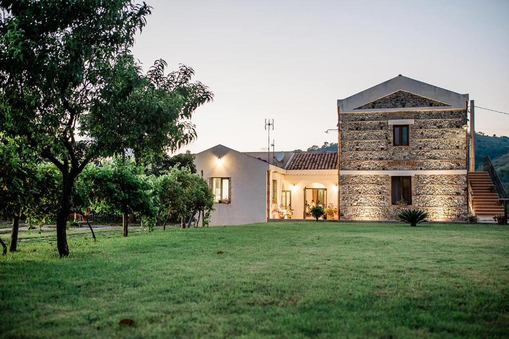 a large house with a grass yard in front of it at Valle degli Agrumi in San Pier Niceto