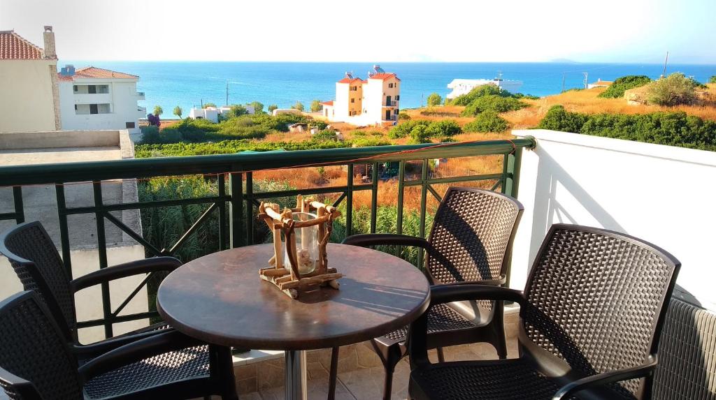 un tavolo e sedie su un balcone con vista sull'oceano di Irides Apartments a Megalochori (Isola di Agistri)