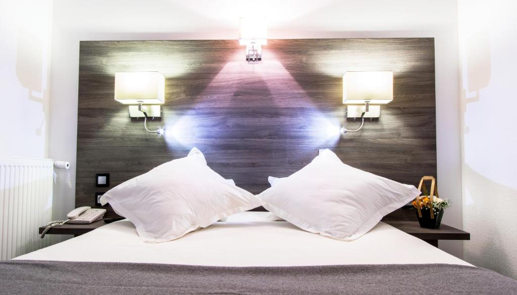 a bedroom with a large bed with two pillows at Hotel Actuel Chambéry Centre Gare in Chambéry