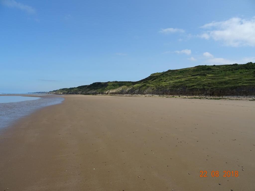 an empty beach with a hill in the background at La ferme aux chats in Formigny