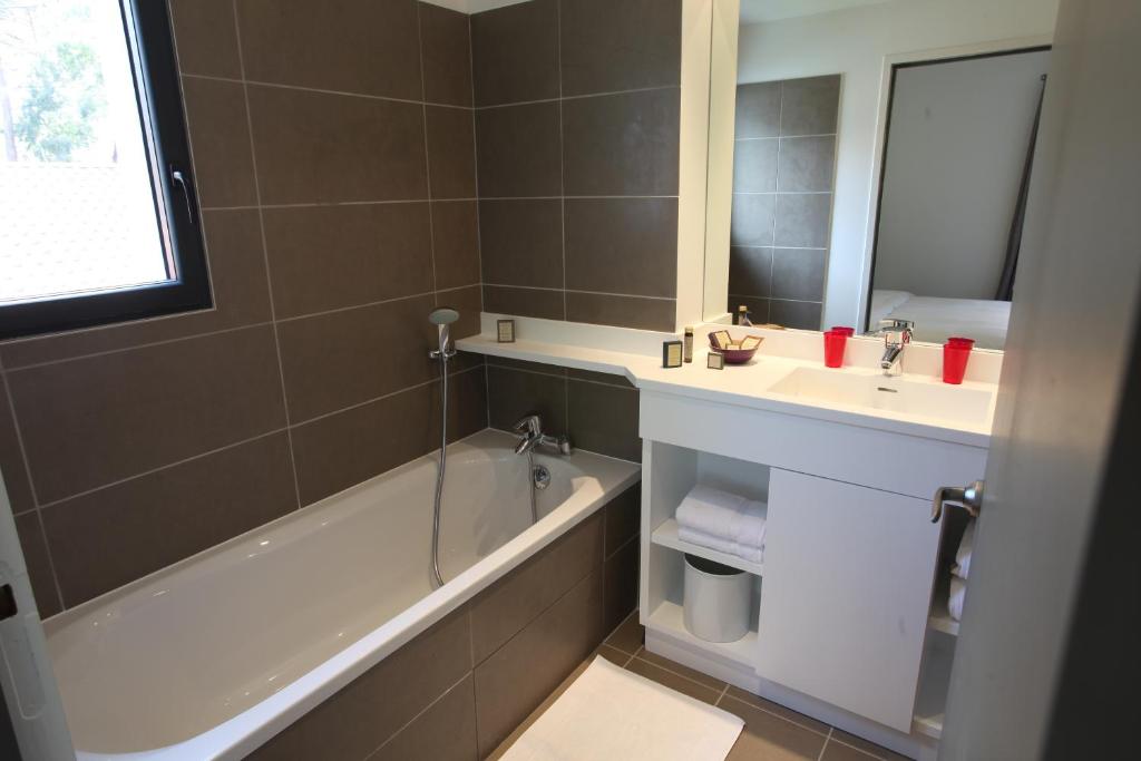 a bathroom with a bath tub and a sink at Hotel 202 in Hossegor