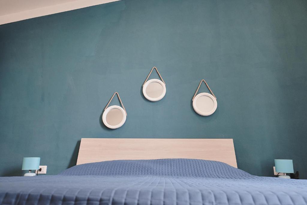a bedroom with a blue wall with four mirrors on the wall at Appartamenti Luxury Greco in Brindisi