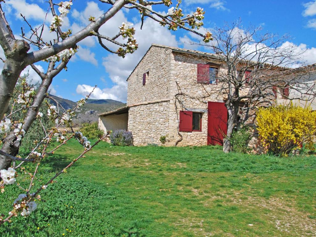 una vieja casa de piedra con una puerta roja en una colina en Holiday Home Les Geais-1 by Interhome en Saint-Saturnin-dʼApt