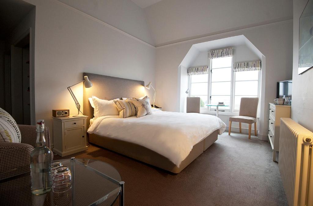 Un dormitorio con una gran cama blanca y una mesa en Crown and Castle, en Orford