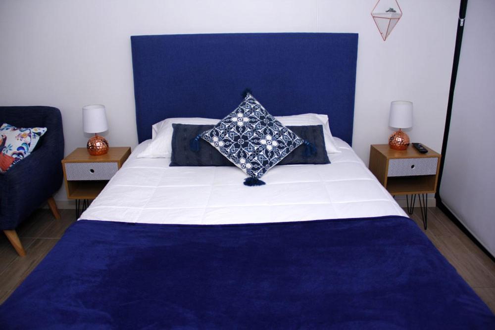 a bedroom with a blue and white bed with two tables at Apartamento de Lujo. Frente Mall Plaza in Antofagasta