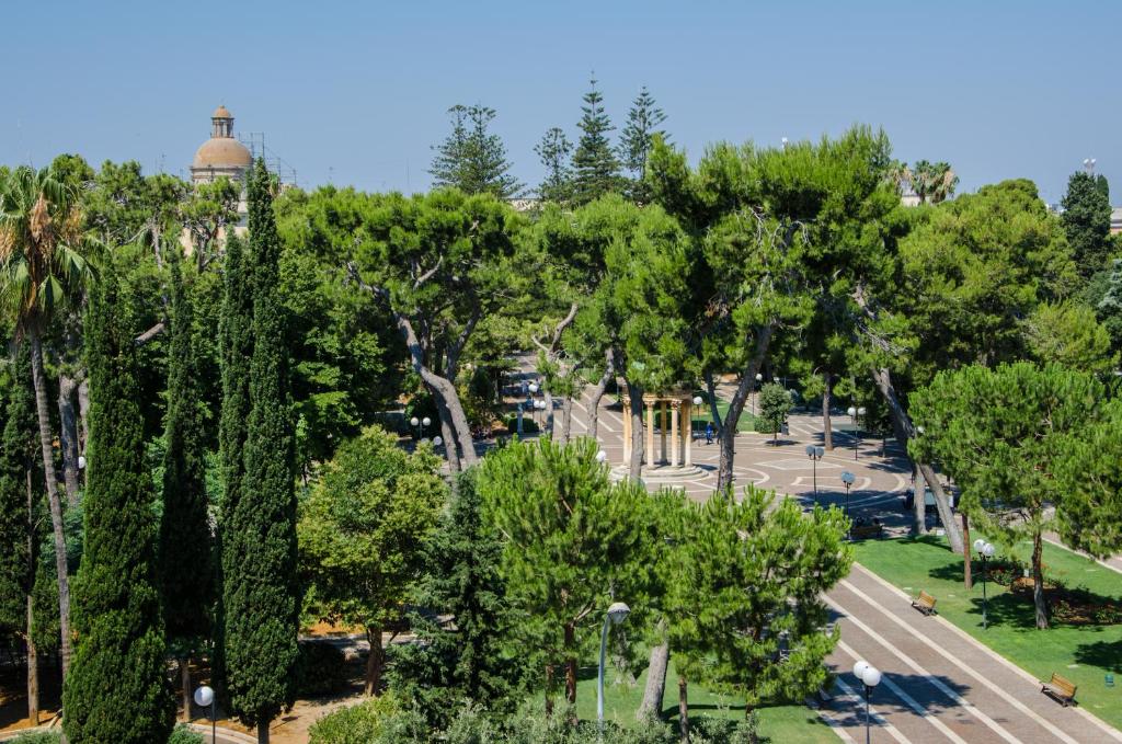 einen Blick über einen Park mit Bäumen und einen Parkplatz in der Unterkunft Larala' in Lecce