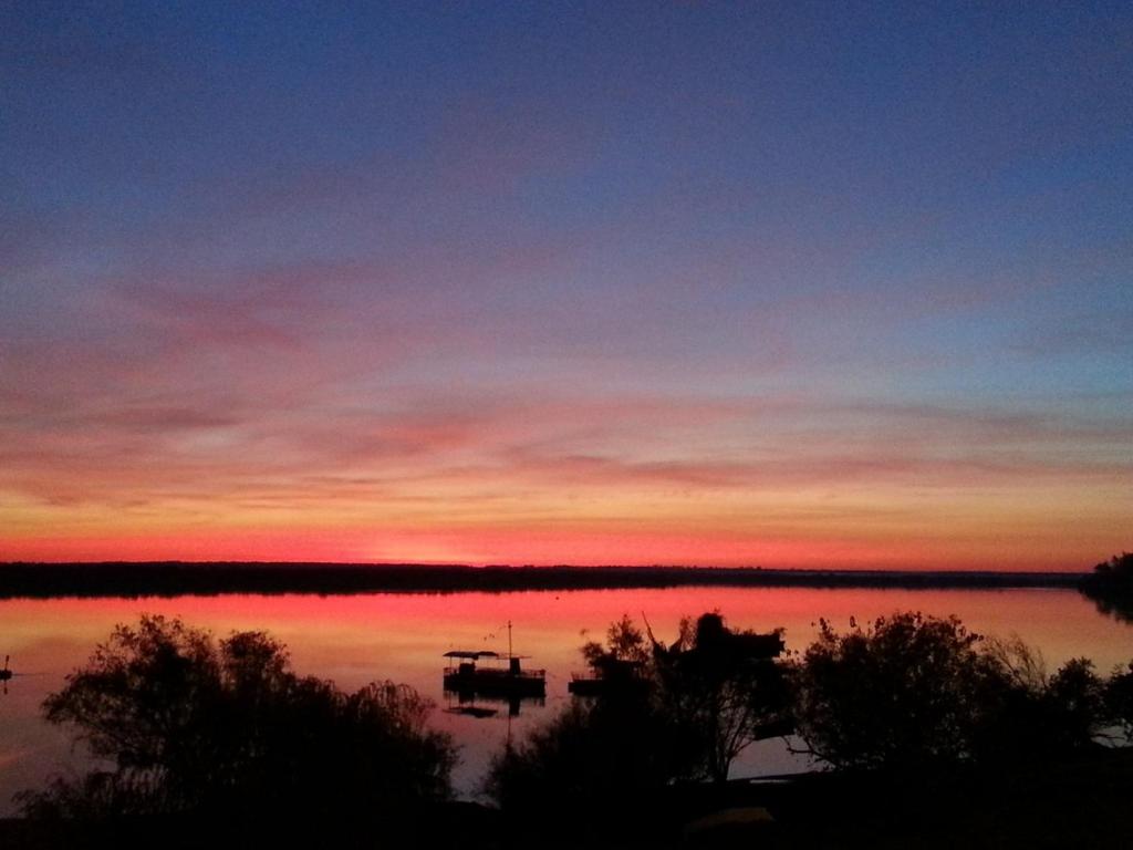 una puesta de sol sobre un lago con un barco en el agua en NorthBeach en Colón