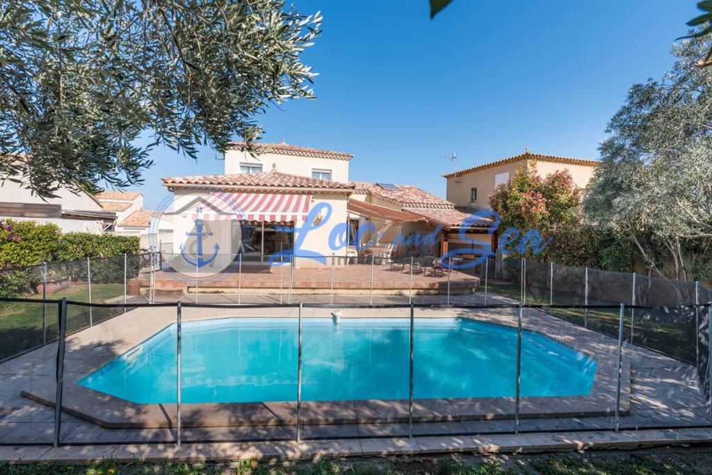 ein Haus mit Pool hinter einem Zaun in der Unterkunft Maison Flamants Roses avec Piscine in Le Grau-du-Roi