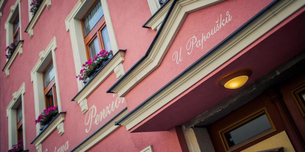 ein rosafarbenes Gebäude mit Blumen auf der Seite in der Unterkunft Penzion U Papoušků in Jindřichův Hradec