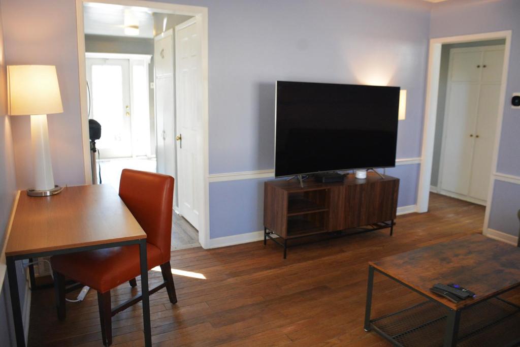 a living room with a flat screen tv and a table at Stunning Downtown Royal Oak Townhouse (909) in Royal Oak