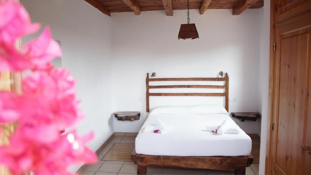 a bedroom with a bed with white sheets and pink flowers at Casa Rustick in Sant Francesc Xavier