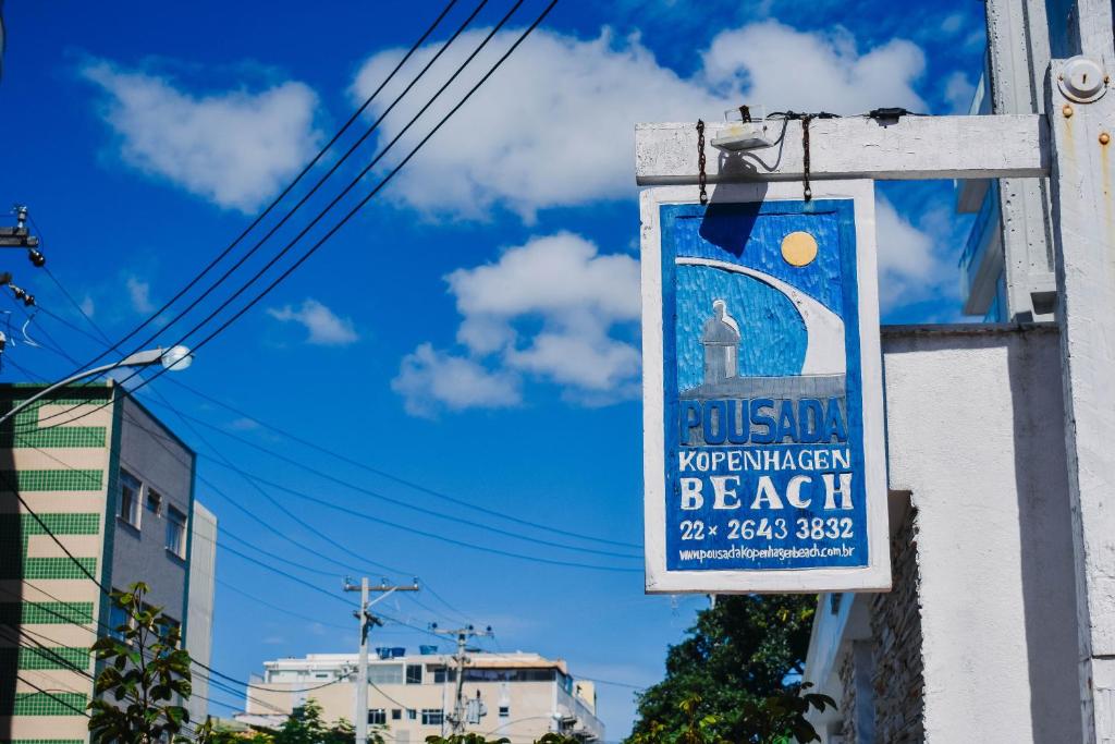 un cartello appeso sul lato di un edificio di Pousada Kopenhagen Beach a Cabo Frio