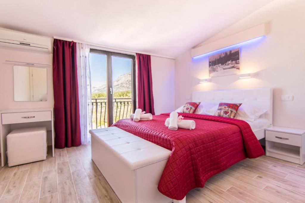 1 dormitorio con 1 cama con colcha roja en Apartments Family Roso, en Promajna