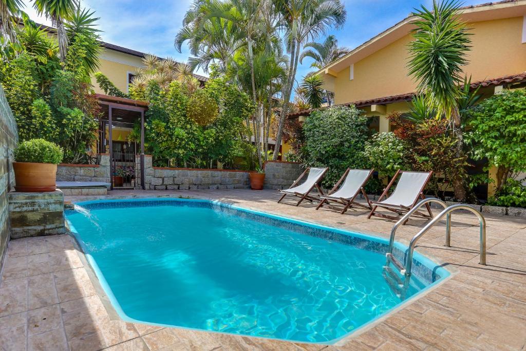 uma piscina com cadeiras e uma casa em Lemuria Apart Hotel em Florianópolis