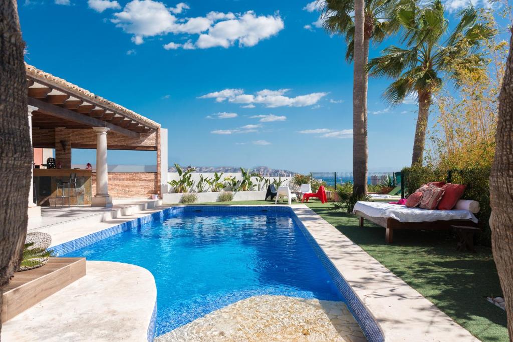 uma piscina num quintal com palmeiras em Villa exclusiva con espectaculares vistas al Mediterráneo em Cala de Finestrat