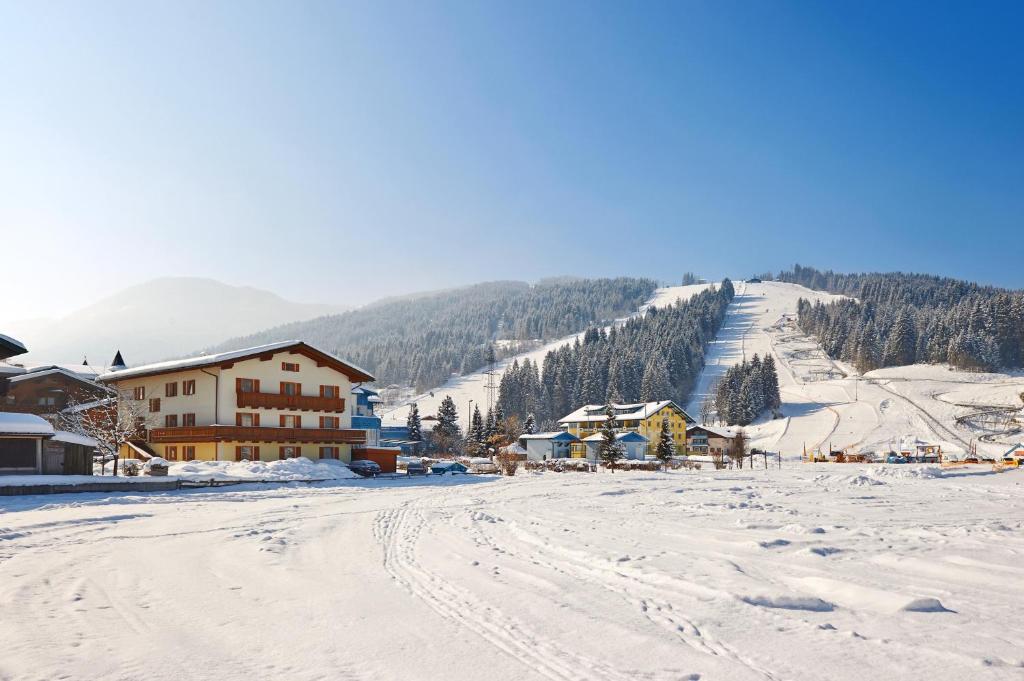 una montaña cubierta de nieve con un lodge de esquí y una pista de esquí en Lärchenhof, en Flachau