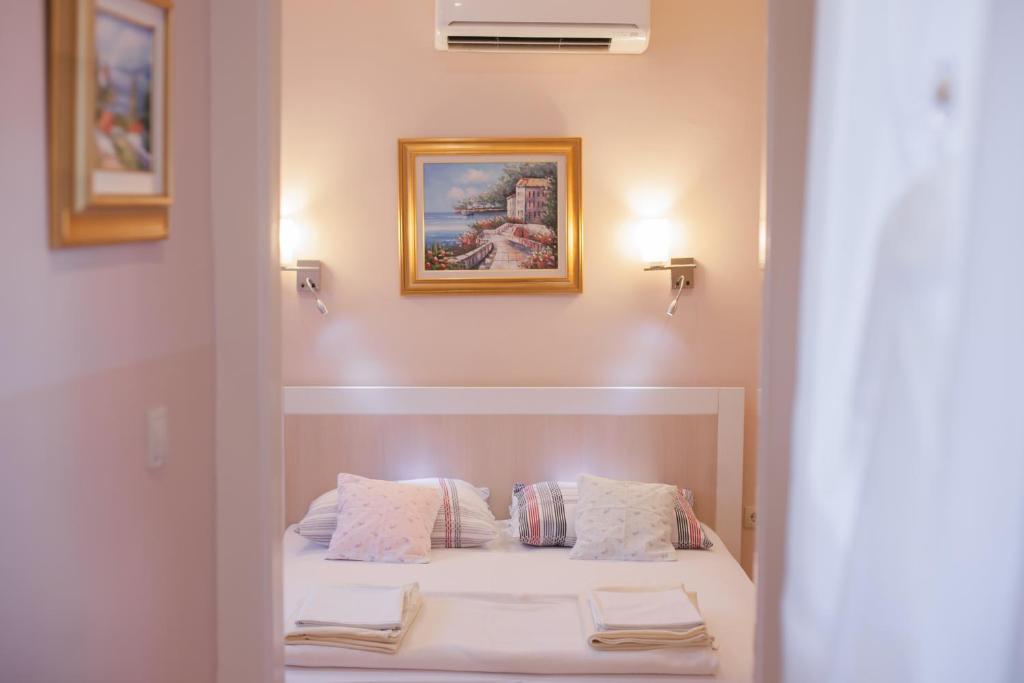 un dormitorio con una cama con sábanas y almohadas blancas en Ba & Bo, en Šibenik