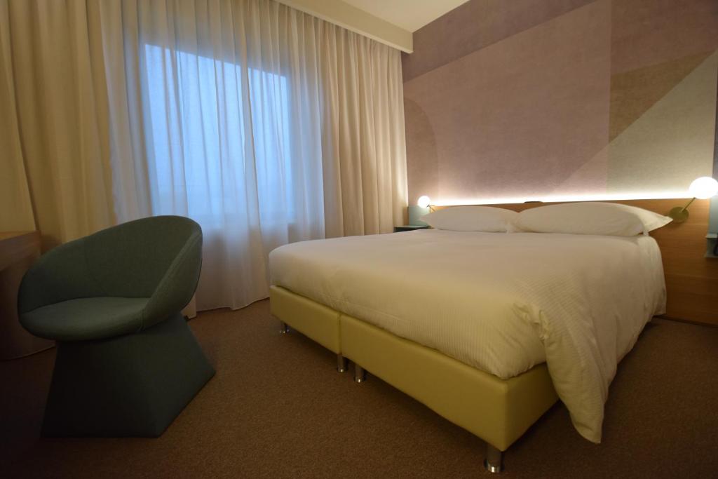 una habitación de hotel con una cama grande y una silla en Garden Hotel, en Arezzo