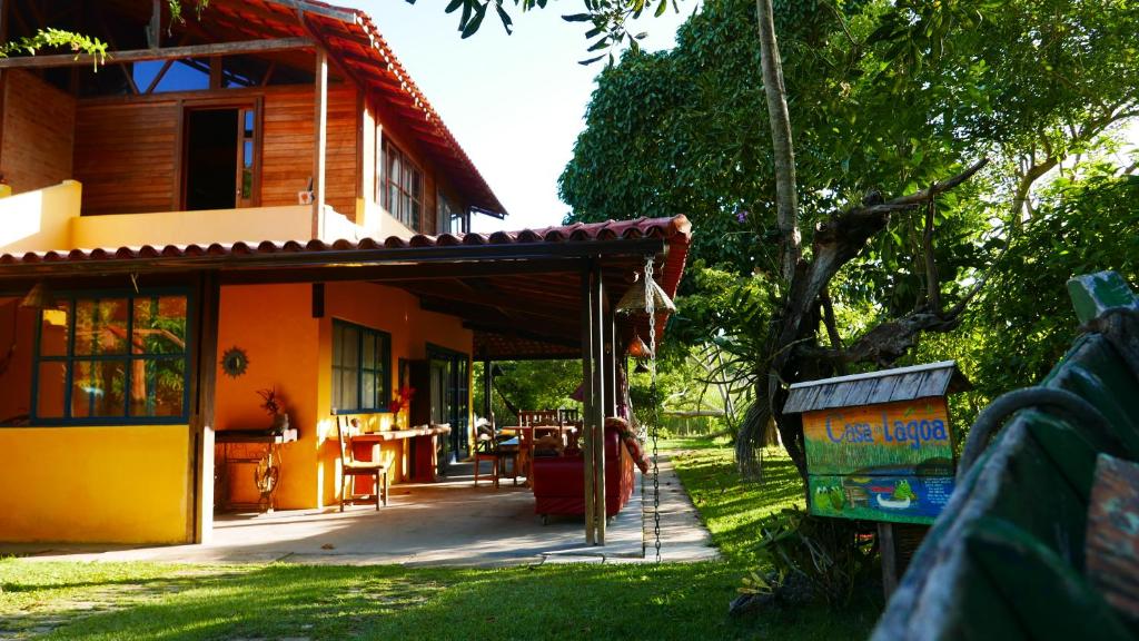 a house with a porch and a table in front of it at Pousada Camping Porto Grande in Meaípe