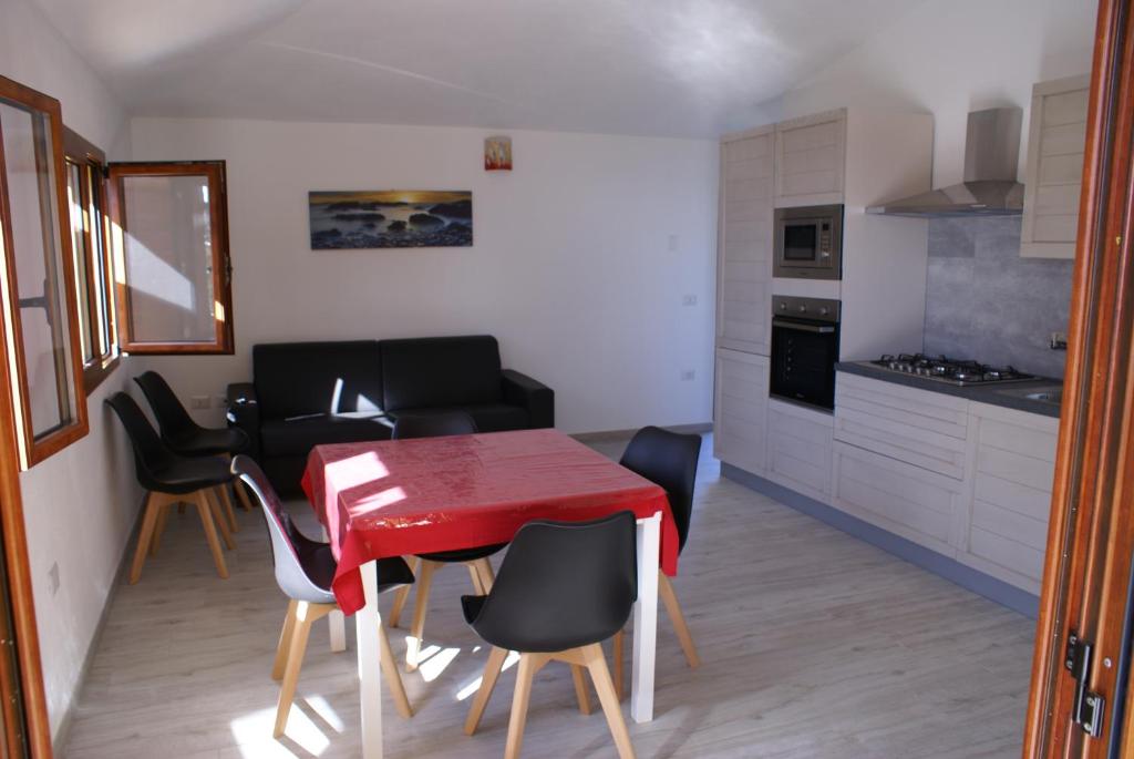 una cucina e una sala da pranzo con tavolo e sedie rossi di casa mariolu 2 piano mansarda a Cala Gonone